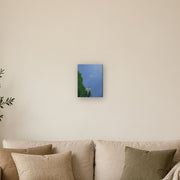 I am a beginning, not an ending canvas print by Artis Berkmanis, a single dandelion seed lifting off into a clear blue sky. Shown at 23 x 30 cm above a sofa in a Scandinavian living room.