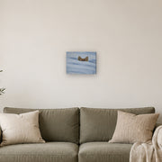 I am not lost, only hiding canvas print by Artis Berkmanis, fox ears rising from soft blue-white snow. Shown at 30 x 23 cm above a sofa in a Scandinavian living room.