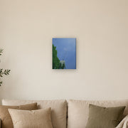 I am a beginning, not an ending canvas print by Artis Berkmanis, a single dandelion seed lifting off into a clear blue sky. Shown at 30 x 41 cm above a sofa in a Scandinavian living room.