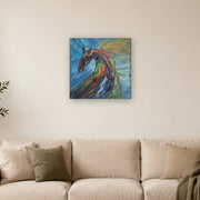 Do not mistake silence for surrender! canvas print by Artis Berkmanis, a wild horse in thick red, green and dark strokes against a blue and yellow sky. Shown at 51 x 51 cm above a sofa in a Scandinavian living room.