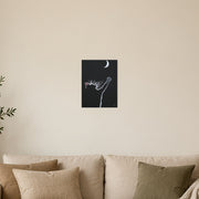 At least I tried art poster by Artis Berkmanis, a small black cat reaching one paw towards a white crescent moon in a dark night sky. Unframed matte print shown at 30 x 40 cm above a sofa in a Scandinavian living room.