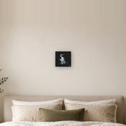 I am not as small as I look canvas print by Artis Berkmanis, a small white kitten stepping out of a black background. Shown at 20 x 20 cm above a bed in a calm Scandinavian bedroom.