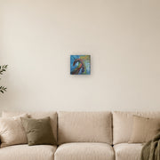 Do not mistake silence for surrender! canvas print by Artis Berkmanis, a wild horse in thick red, green and dark strokes against a blue and yellow sky. Shown at 20 x 20 cm above a sofa in a Scandinavian living room.