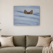 I am not lost, only hiding canvas print by Artis Berkmanis, fox ears rising from soft blue-white snow. Shown at 81 x 61 cm above a sofa in a Scandinavian living room.
