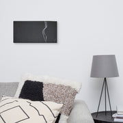 Intimacy? canvas print by Artis Berkmanis on a light grey wall above a bed with patterned pillows and a lamp